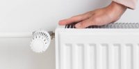 A woman warming her hands on a heating radiator, the concept of conserving heat and energy and the importance of resource management during colder seasons. seeking warmth, energy efficiency, and mindful living
